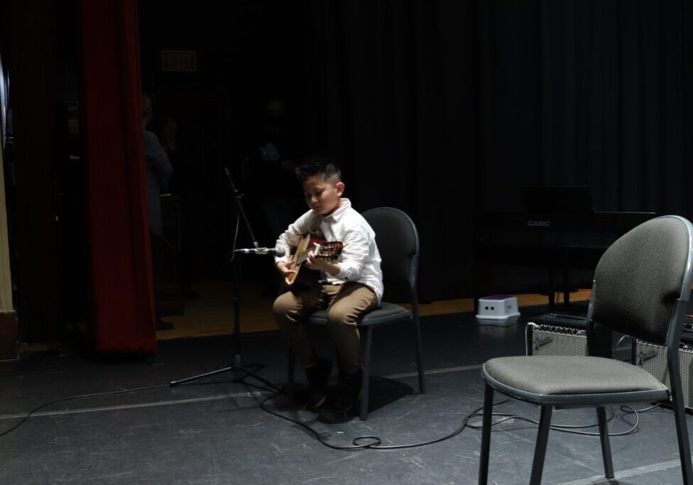 young kid playing guitar on stage